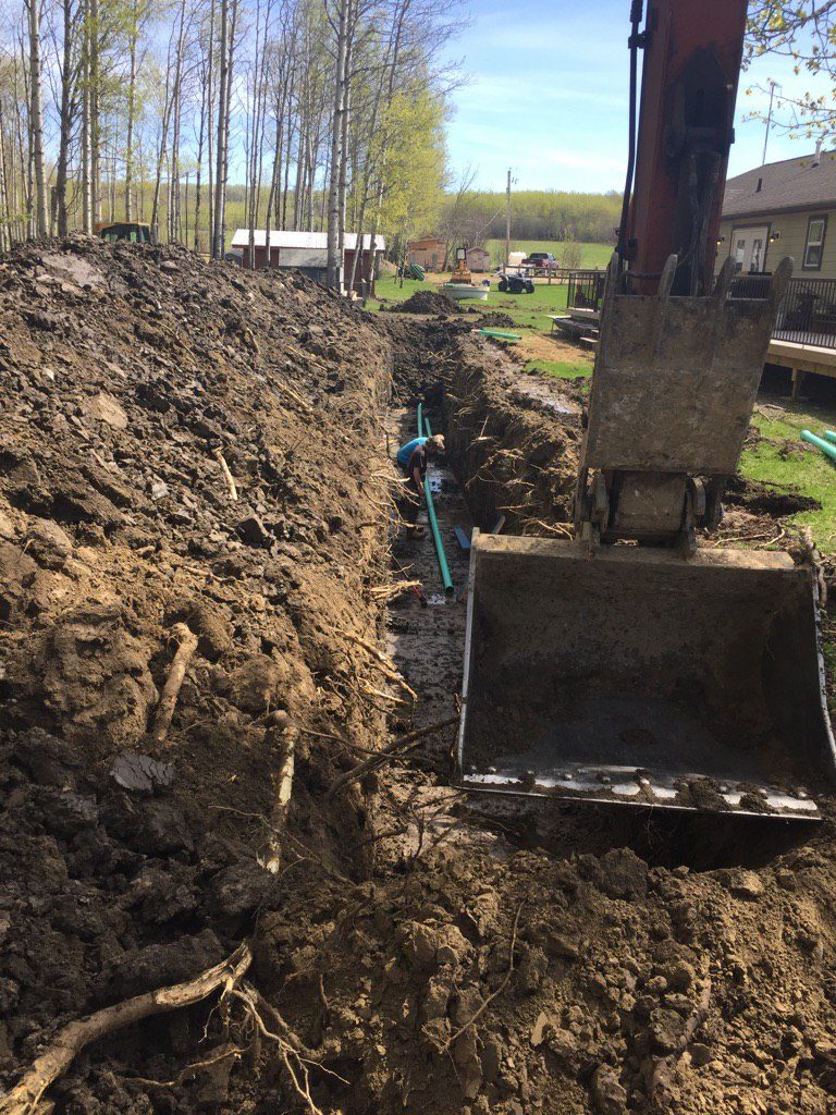 LandScaping Dawson Creek Photo Trenching From House To Lagoon And Placing Pipe At The Same Time